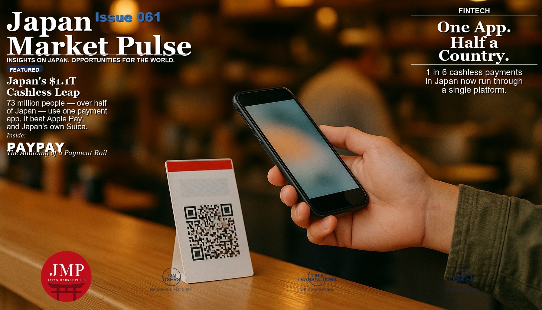 A customer holds a smartphone over a small printed QR-code payment sign at the counter of a cozy Japanese noodle shop, with the warm interior blurred in the background.